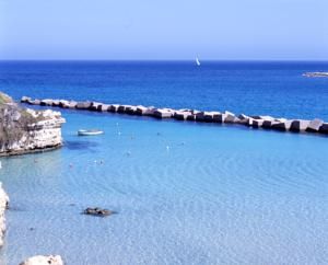 Piccola baia con mare turchese, barca e scogli.