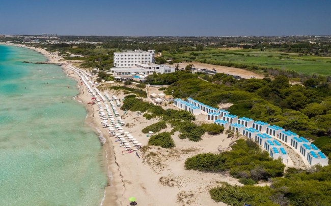 Spiaggia con ombrelloni bianchi e mare azzurro.
