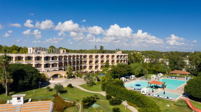 Hotel con piscina circondata da giardini.