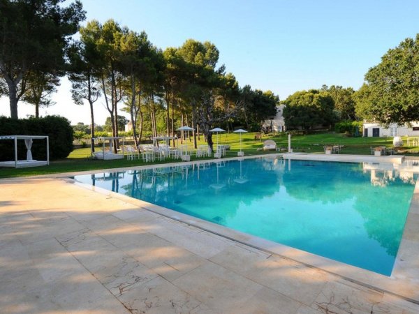Piscina esterna con alberi intorno e cieli sereni.