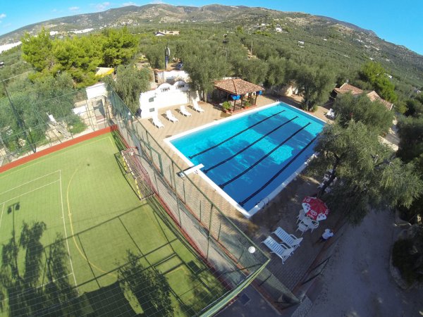 Piscina rettangolare accanto a un campo da calcio.