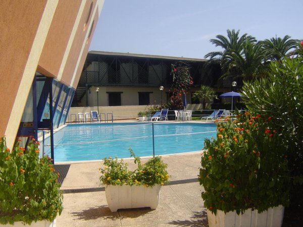 Piscina con lettini e piante.