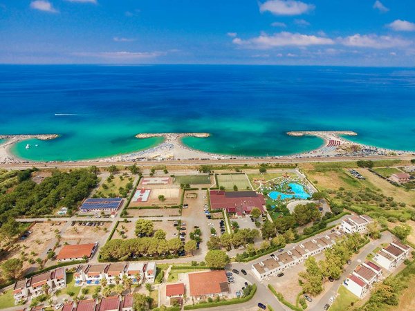 Vista aerea di spiaggia con acque turchesi e stabilimento balneare.