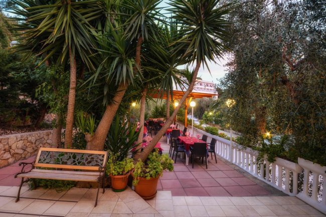 Terrazza esterna con tavoli e sedie tra le piante.