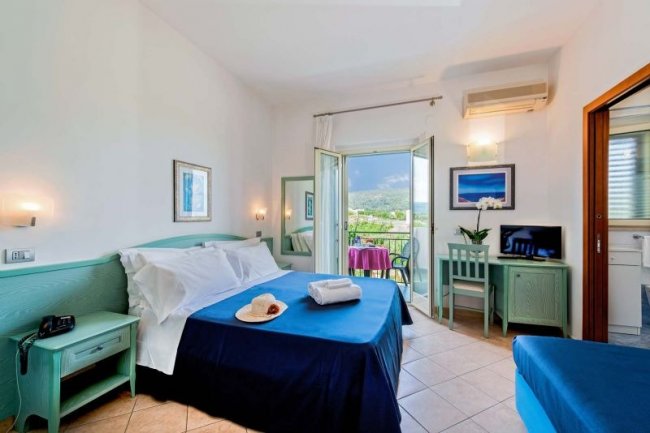 Camera con letto matrimoniale blu e balcone.
