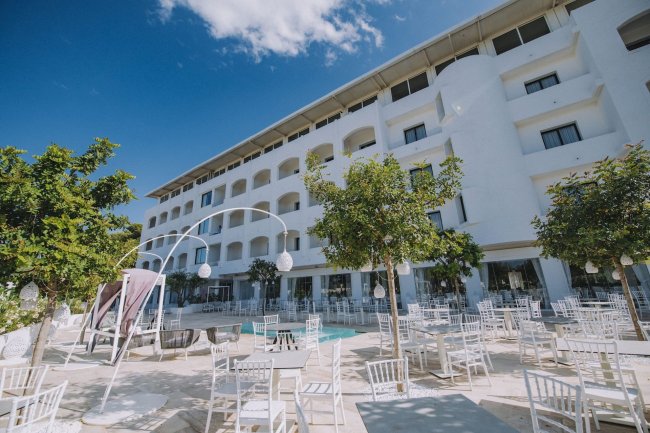 Edificio bianco con area esterna arredata.