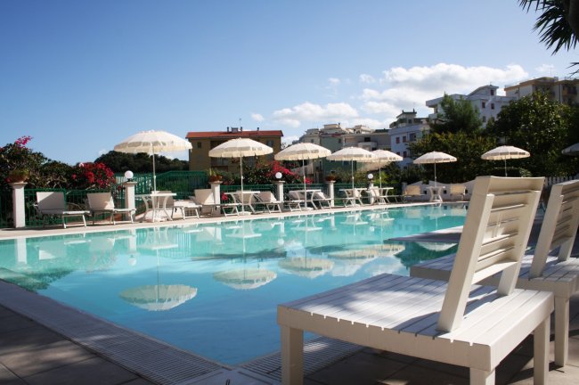 Piscina con lettini e ombrelloni bianchi.