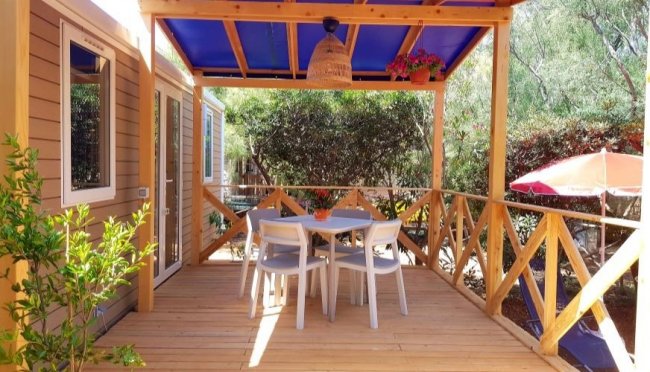 Veranda con tavolo e sedie sotto tettoia blu.