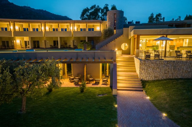 Hotel illuminato di sera con giardino.