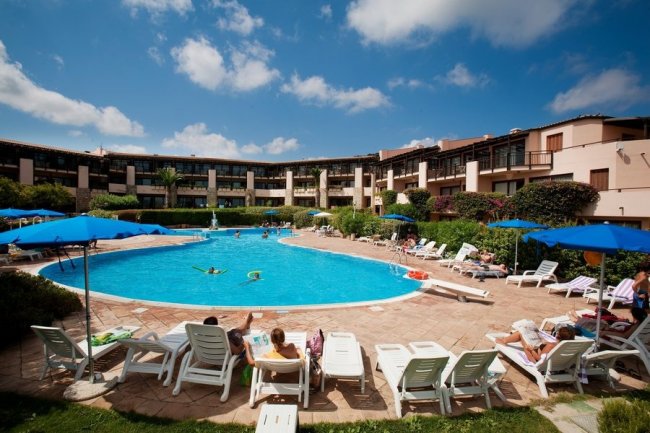 Piscina soleggiata con persone che nuotano e sdraio.