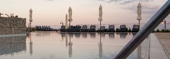Sdraio e ombrelloni riflessi in piscina.