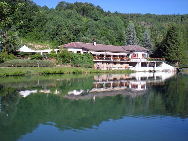 Casa sul lago circondata da alberi, riflessa nell'acqua.