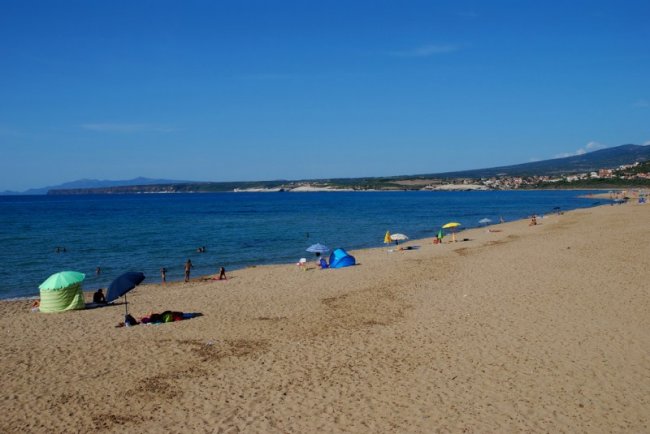 Una lunga spiaggia sabbiosa con mare blu.