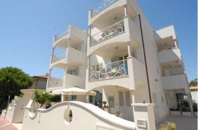 Un edificio bianco con balconi e dettagli architettonici eleganti, cielo blu sullo sfondo.