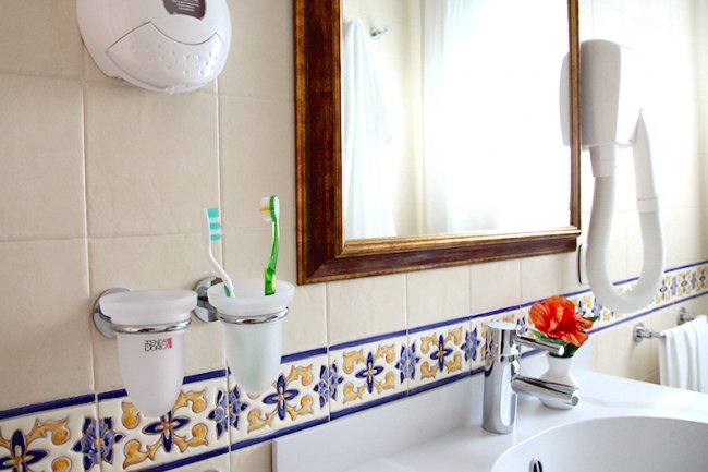 Lavabo in bagno con spazzolini e piastrelle decorate.