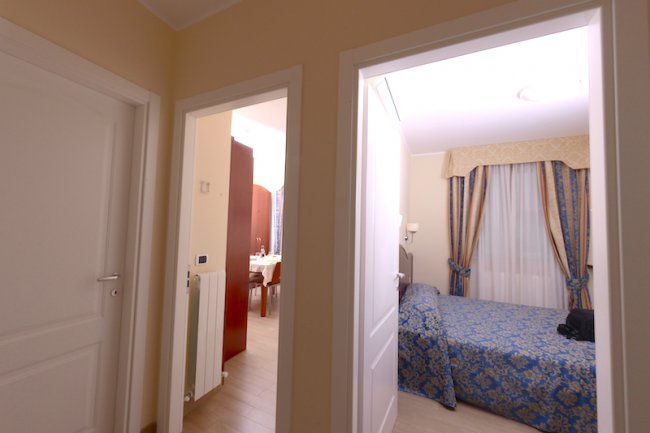 Due porte aperte su camere, una da letto e una sala.