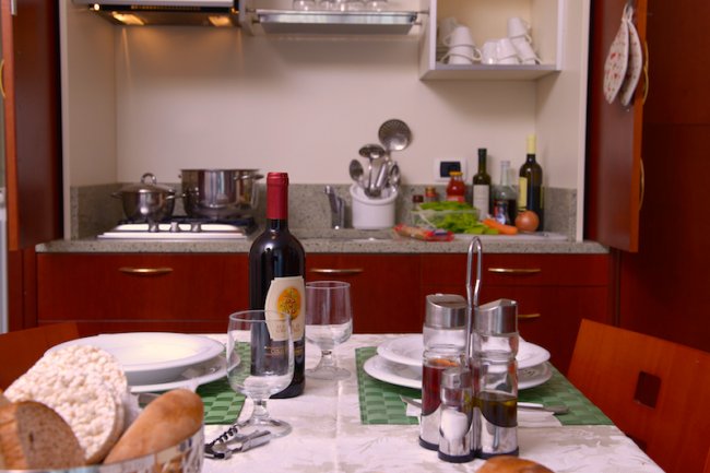 Una cucina con tavola apparecchiata e bottiglia di vino.