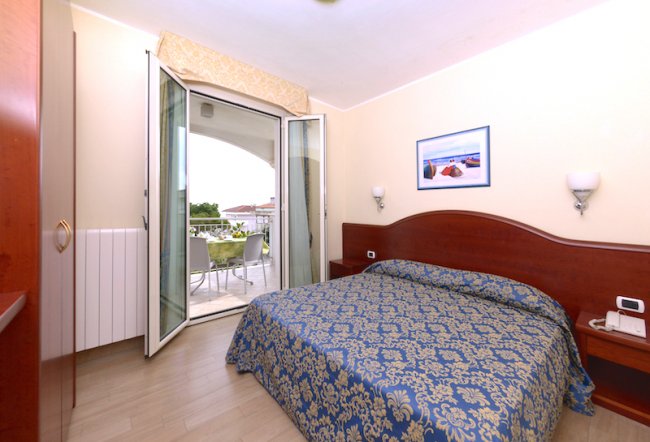 Camera da letto con letto matrimoniale e balcone.