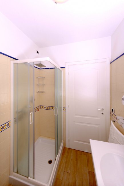 Bagno con doccia e porta bianca.