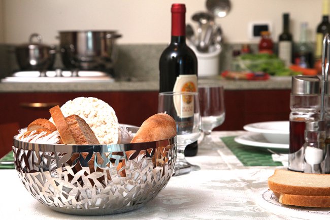Tavolo apparecchiato con pane e bottiglia di vino.