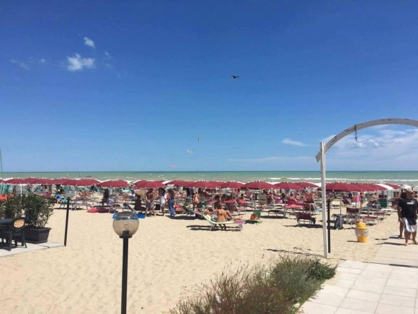 Spiaggia con ombrelloni rossi e lettini.