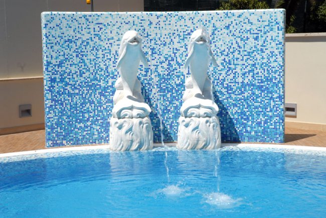 Scultura di delfini su sfondo di piastrelle blu.