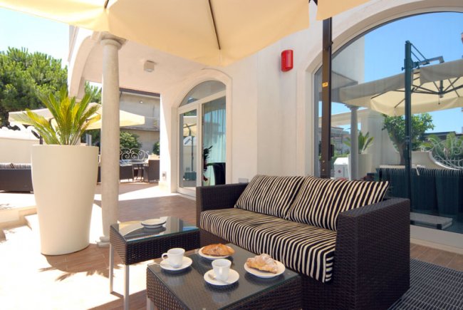 Area esterna con divano e tavolino sotto un ombrellone.