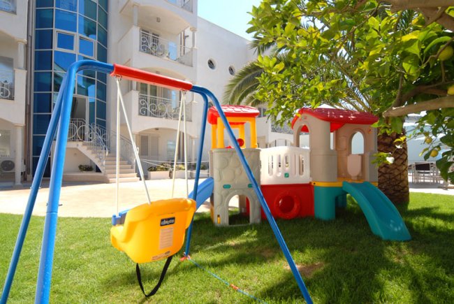 Gioco per bambini con altalena e scivolo su prato.