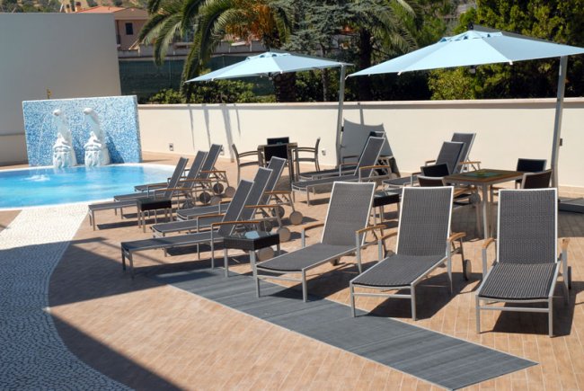 Lettini e ombrelloni vicino a una piscina.