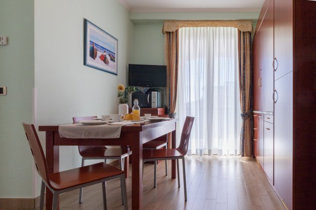 Sala da pranzo luminosa con tavolo apparecchiato.