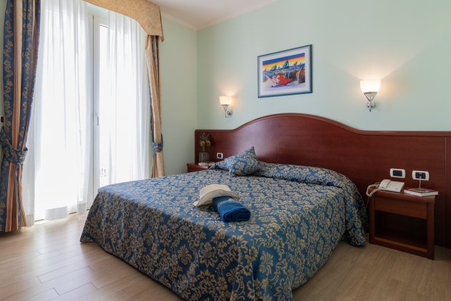 Letto matrimoniale con copriletto blu a motivi floreali.