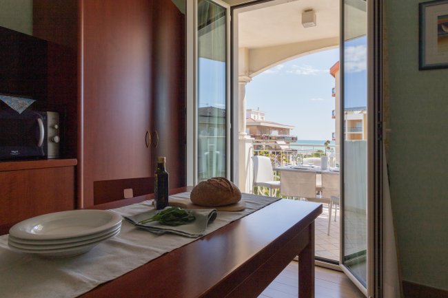 Tavolo apparecchiato con vista sul balcone e mare.