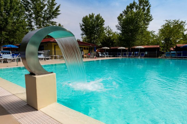 Piscina con cascata d'acqua e lettini.