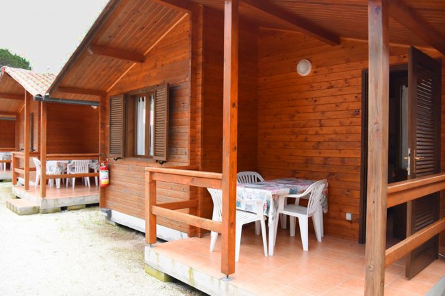 Due bungalow in legno con veranda e tavolo all'aperto.