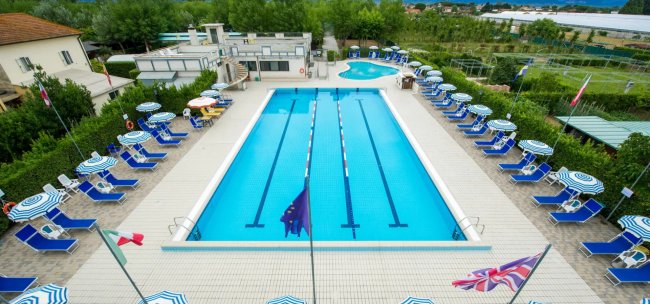 Piscina con sdraio e ombrelloni blu.