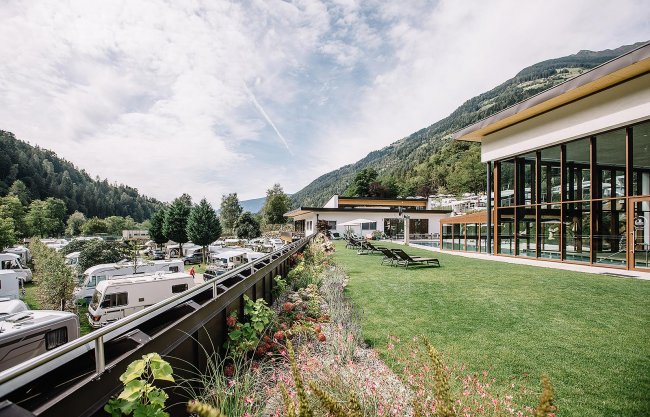 Edificio moderno con ampie vetrate, prato verde con lettini.