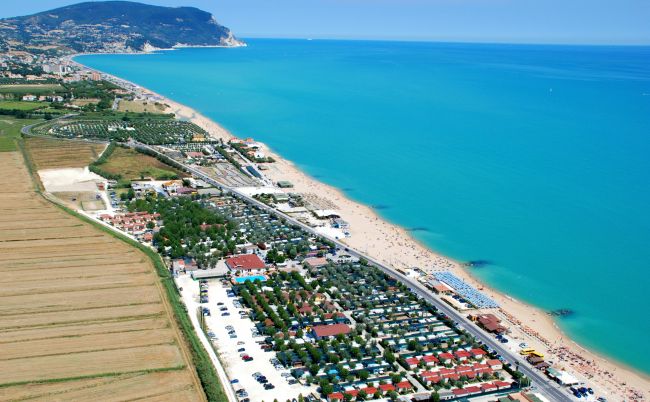 Veduta aerea di una spiaggia con acque turchesi e un resort vicino alla costa.