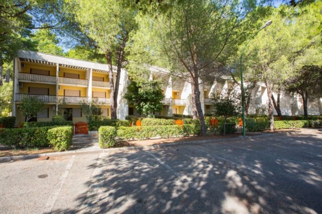 Edificio immerso tra alberi e arbusti.