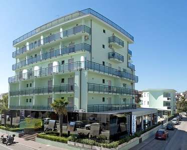 Un edificio moderno a più piani con balconi e pareti di colore verde chiaro.