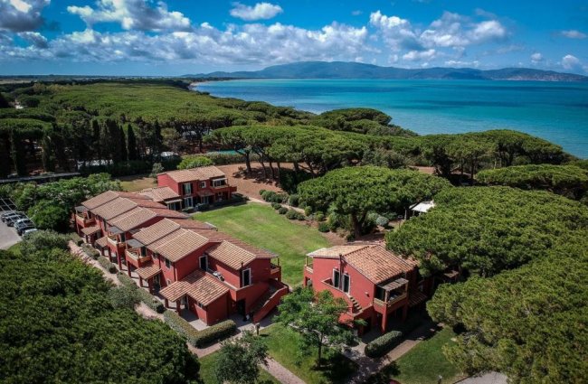 Complesso di edifici rossi circondati da alberi, vicino al mare.