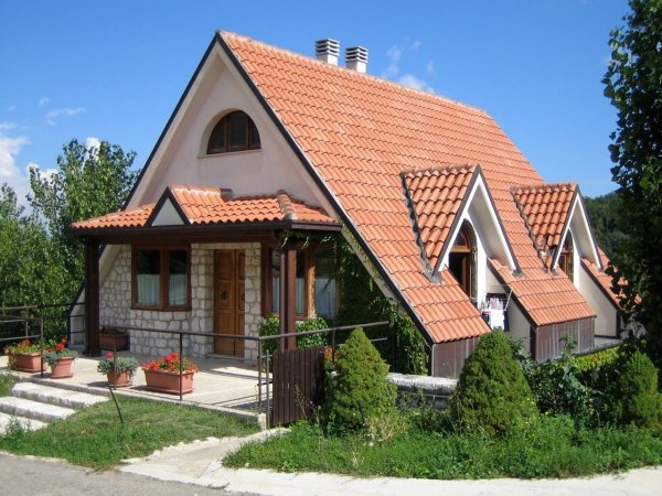 Casa con tetto spiovente e giardino verde.