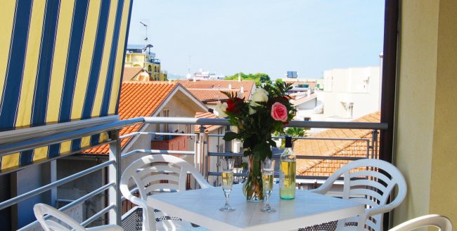Balcone con tavolo, fiori e vista sui tetti.