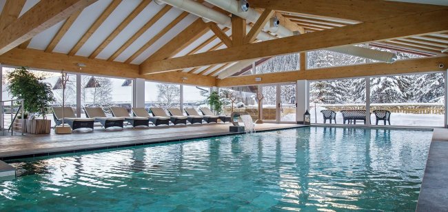Piscina coperta con lettini e vista sulla neve esterna.