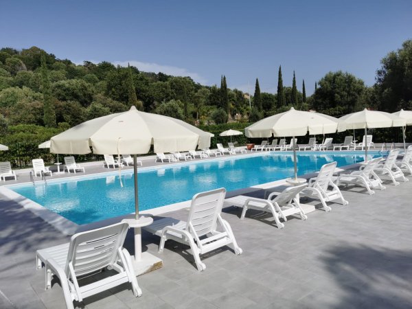 Piscina con sdraio e ombrelloni bianchi.
