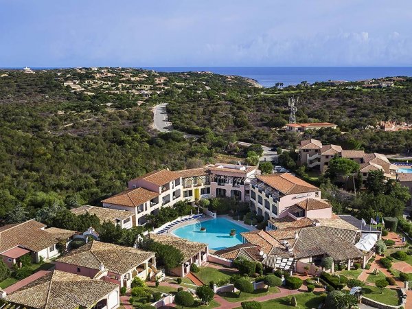 Resort con piscina circondato da colline e vista mare.