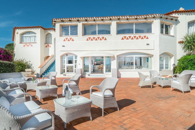 Terrazza con sedie in vimini e tavolini bianchi.