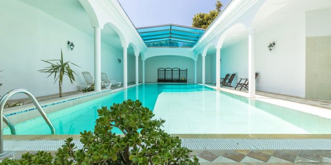 Piscina interna con colonnato bianco.