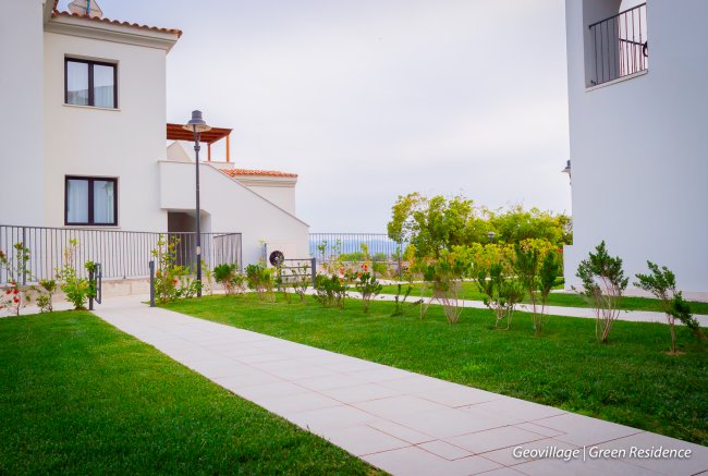 Giardino curato tra edifici bianchi.