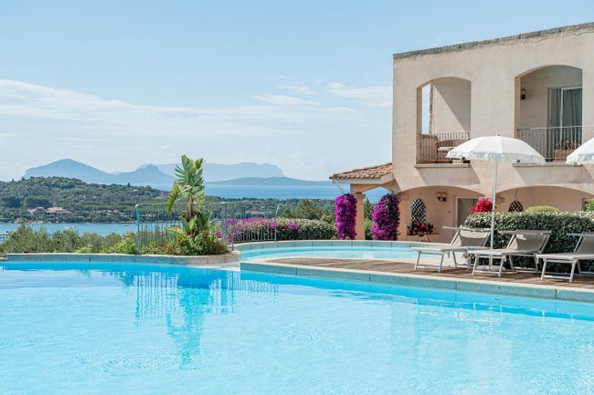 Piscina con vista panoramica sul mare e montagne in lontananza.