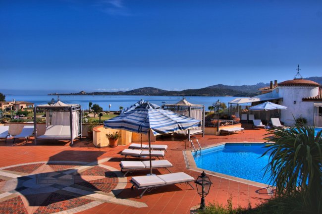 Piscina con lettini e ombrelloni, vista sul mare.